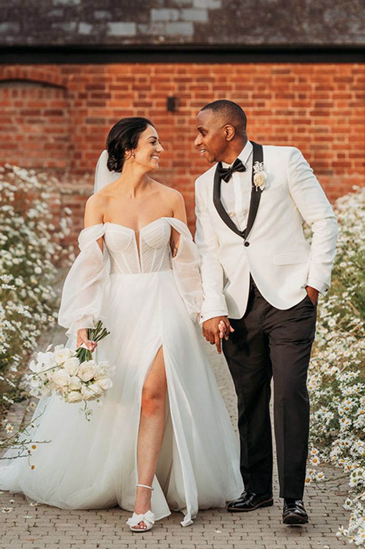 Bride in off the shoulder long sleeve wedding dress with groom in white tuxedo at West Midlands wedding 