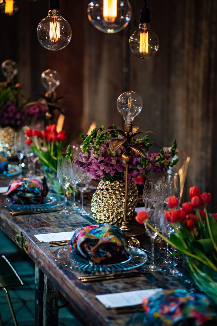 Tropical wedding table decorations with parrots, foliage and Edison bulbs decor 