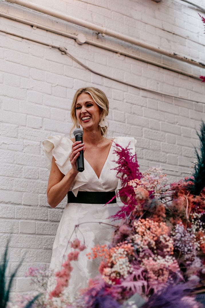 Bride making wedding speech in ruffle wedding dress