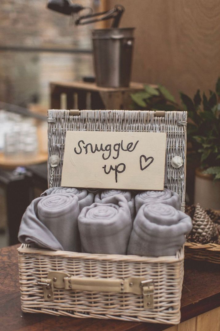 Small wicker basket full of blankets with a sign reading 'Snuggle Up'