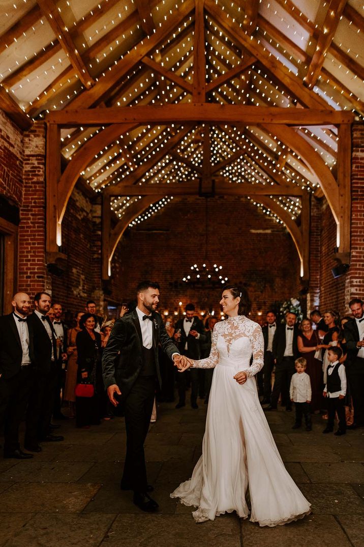 Bride in long sleeve lace wedding dress dancing with groom at barn wedding 