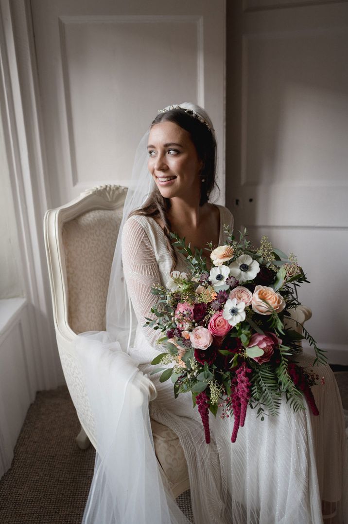 Bride in an embellished Eliza Jane Howell wedding dress holding a peach, pink and white wedding bouquet with roses and anemones 