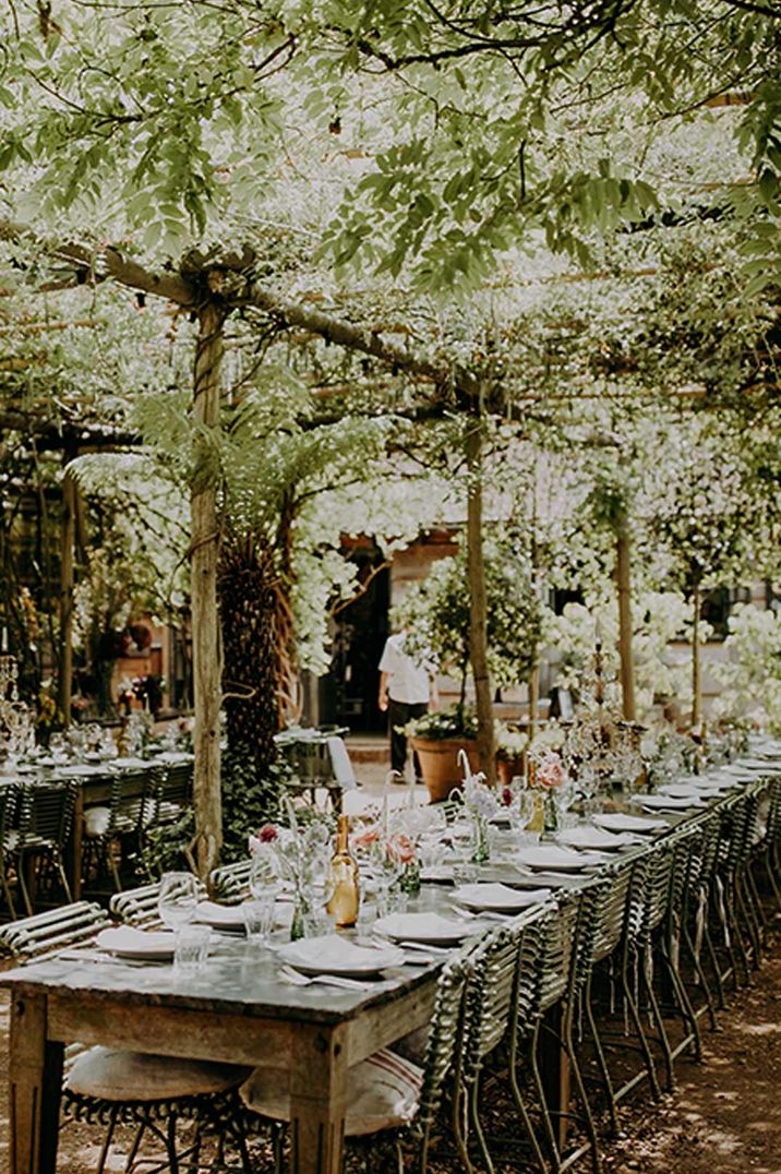 Botanical, neutral wedding tablescape underneath foliage covered roof at Petersham Nurseries glasshouse wedding venue 