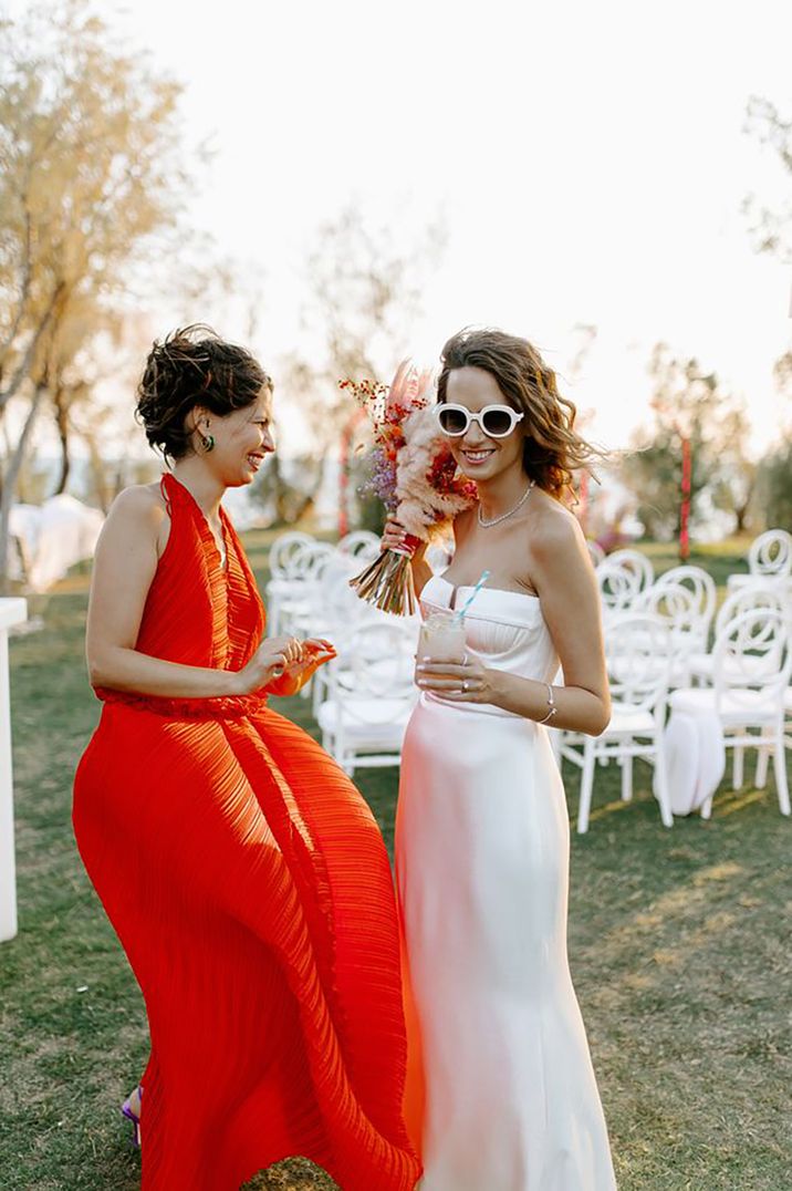 Bride with wedding guest wearing a bride orange halterneck summer wedding guest dress by Brian Robinson Photography