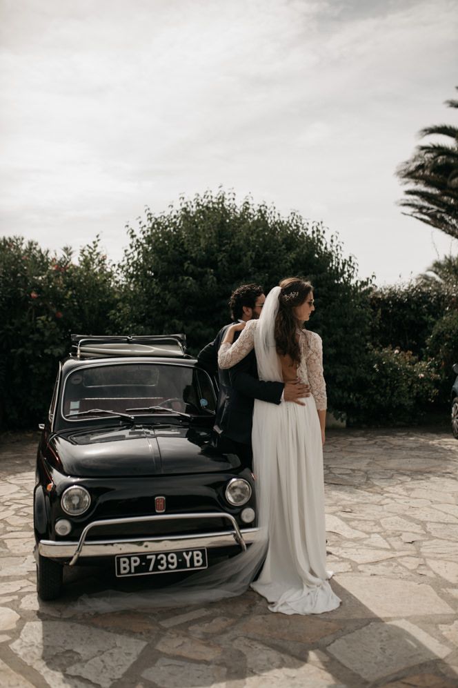 Bride in groom in sunglasses standing by a classic black Fiat 500 wedding car