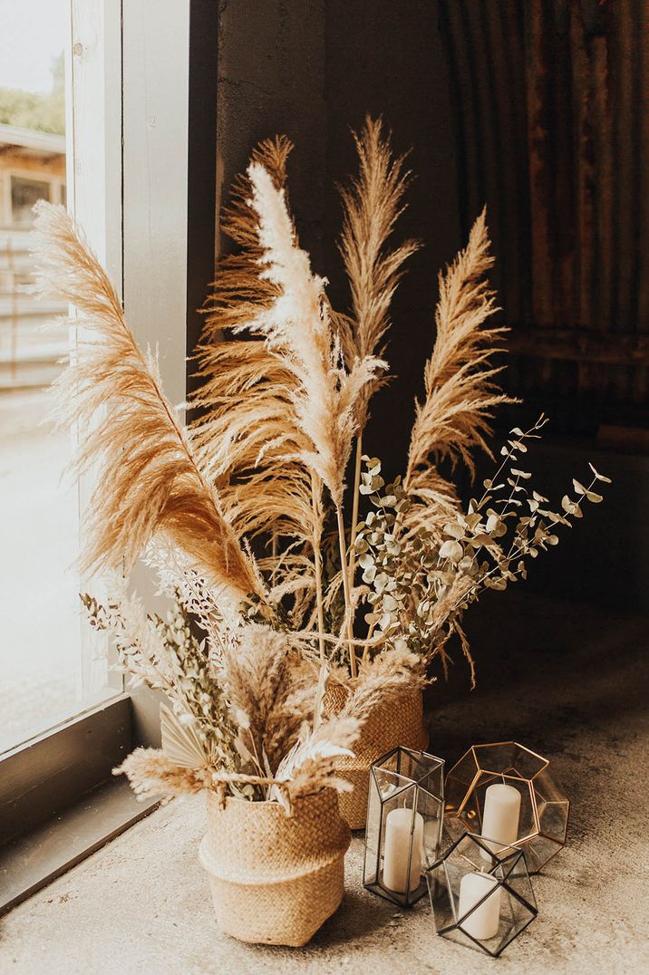 Pampas grass decor in wicker baskets with pillar candles in geometric holders 