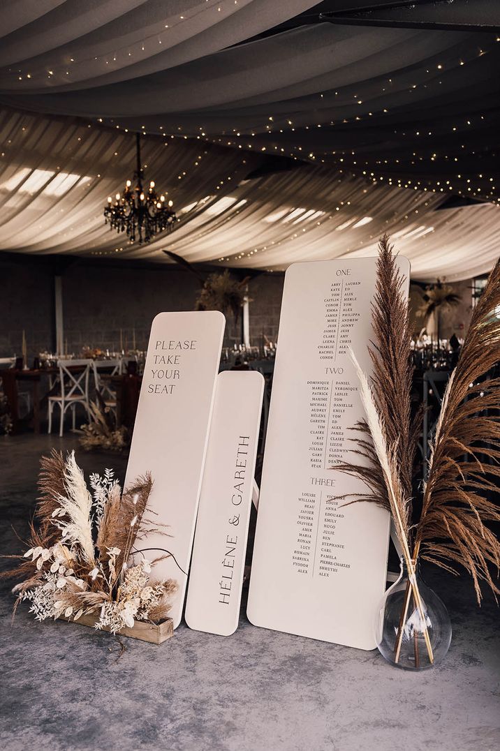 Three large black and white wooden plank table plans with pampas grass displays