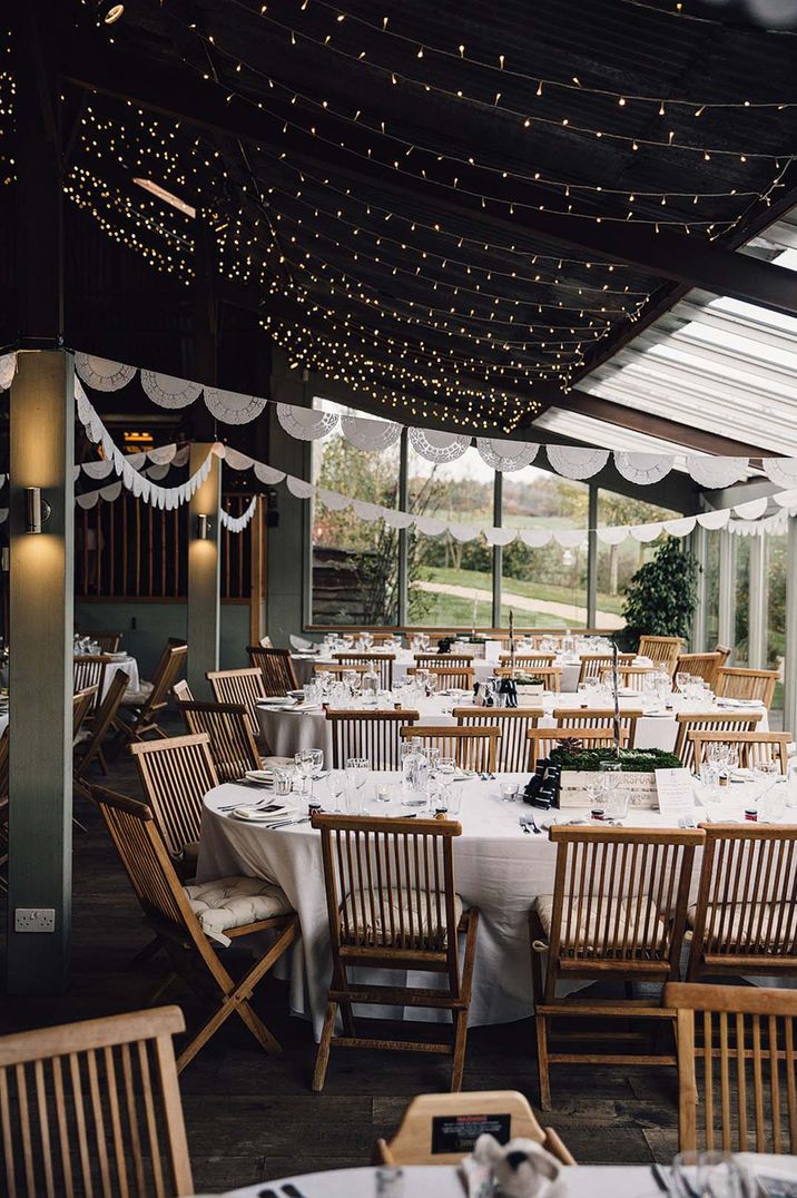 Barn wedding venue reception room with minimalist tablescapes and white paper bunting decoration