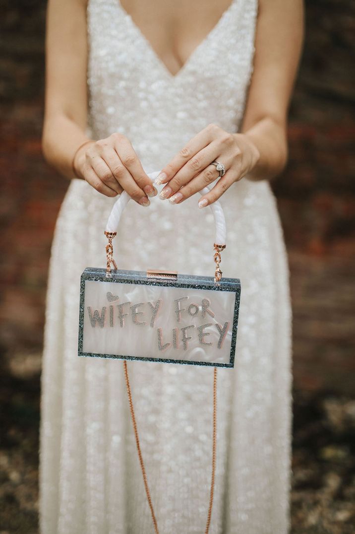 Bride holds Wifey For Lifey handbag with white strap