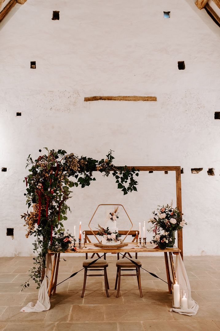 A boho wedding with natural wood decorations, foliage, roses and three tier wedding cake 