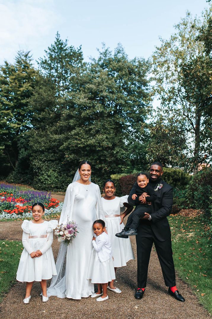 The pregnant bride and groom pose with their children on their wedding day at intimate wedding 