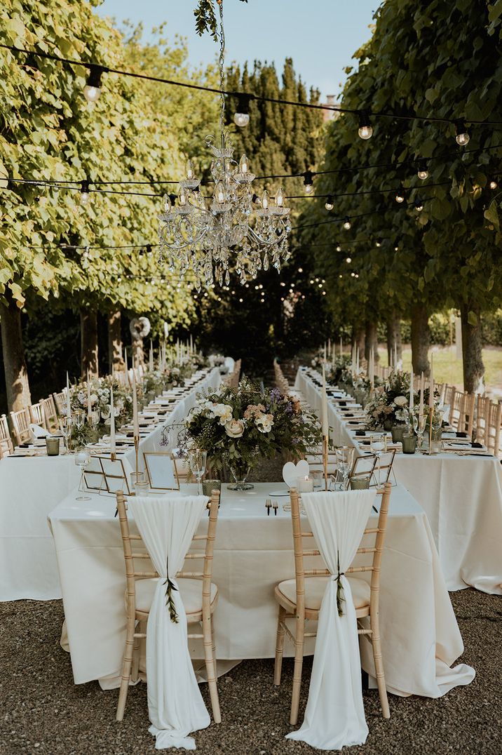 Sweetheart table with the chairs decorated with white fabric and foliage 