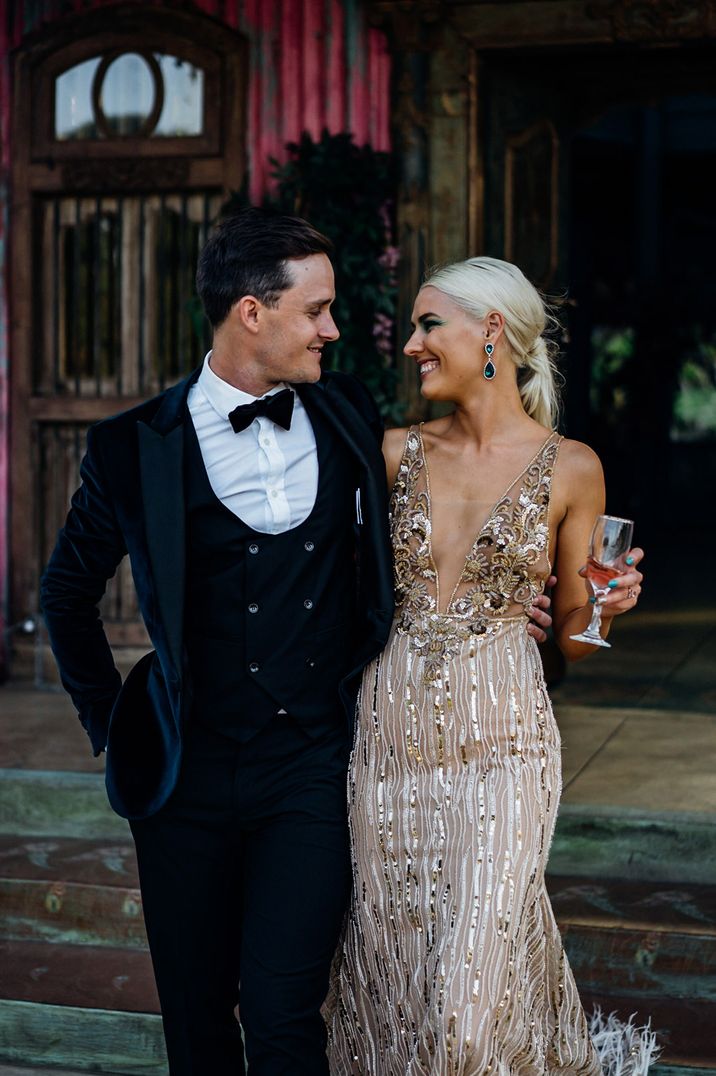 Groom in a tuxedo with horseshoe waistcoat and bow tie and bride in a white and gold sparkly wedding dress 