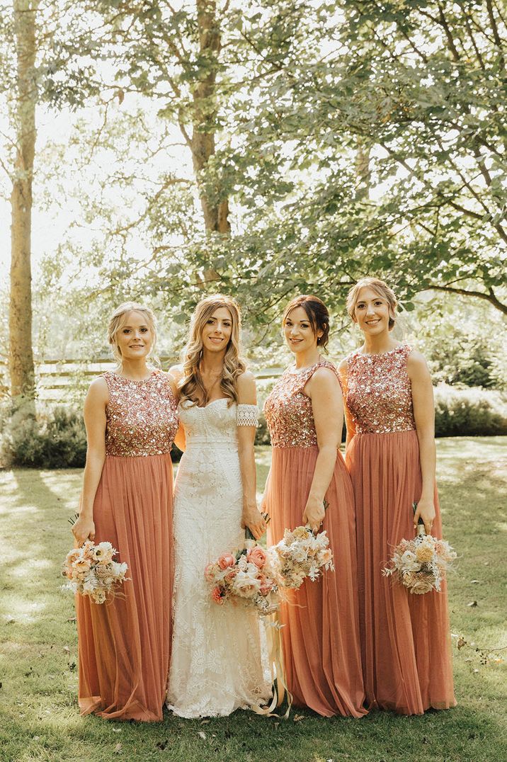 Bride in boho strapless lace wedding dress with the bridesmaids in sparkly orange dresses