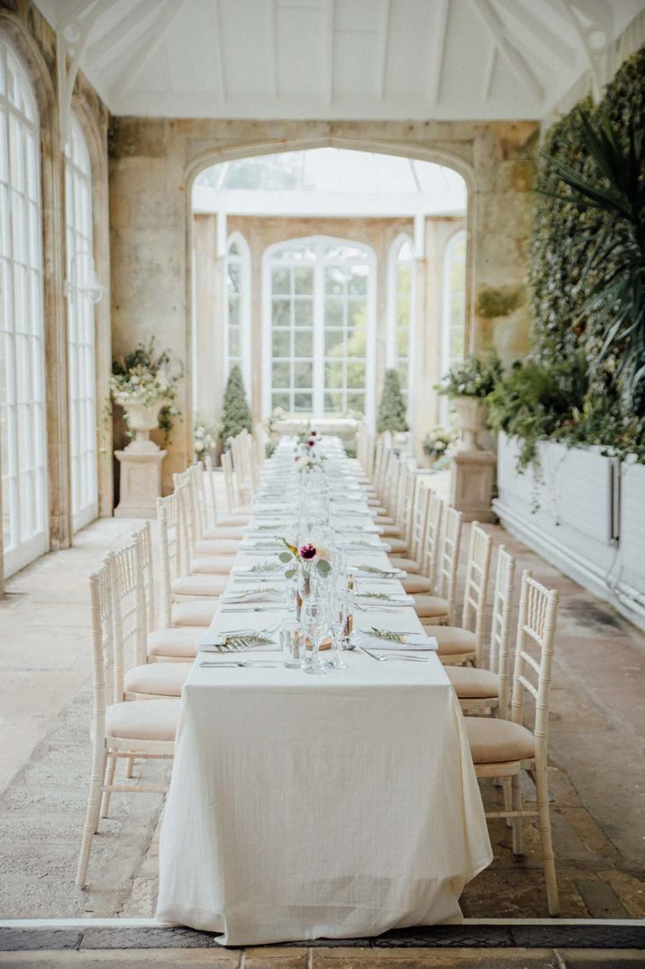 Crisp white wedding tablescape with simple and delicate rose centrepieces and white tablecloths at Crom Castle glasshouse wedding venue 