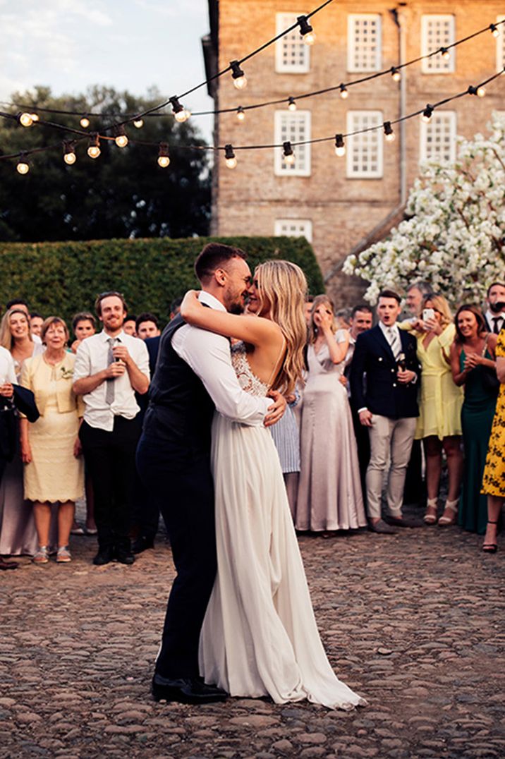 The bride and groom embrace each other in a slow dance 