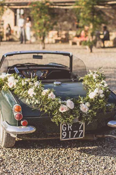 Classic green convertible wedding car with large floral decorations