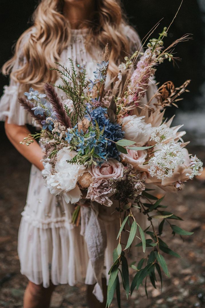 Bride holding pale pink and blue wedding bouquet with wildflowers for under 5k wedding 