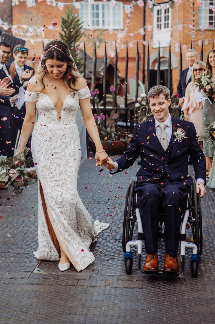 Bride in off shoulder lace wedding dress and groom in dark suit doing confetti throw at Henley Brewery 