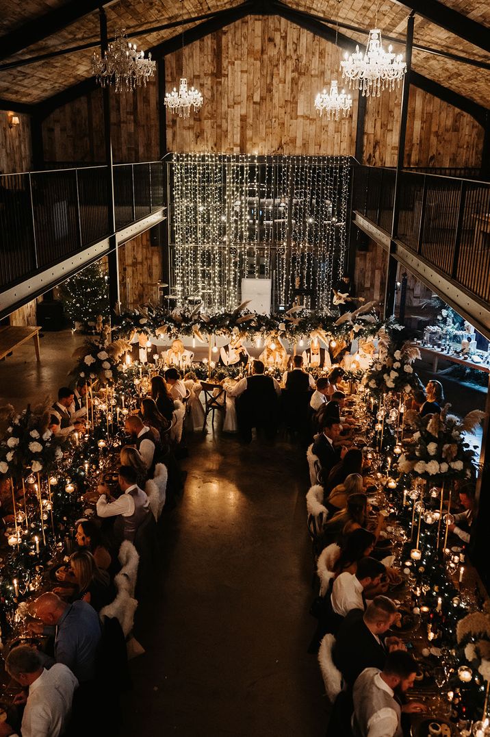 Wedding venue decorated with fairy lights, chandeliers and festoon lighting above the tables 