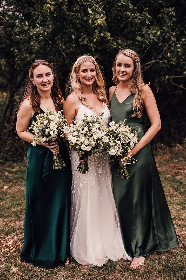 Bride standing with bridesmaids in mismatched green satin bridesmaid dresses for bride to be gift box competition 