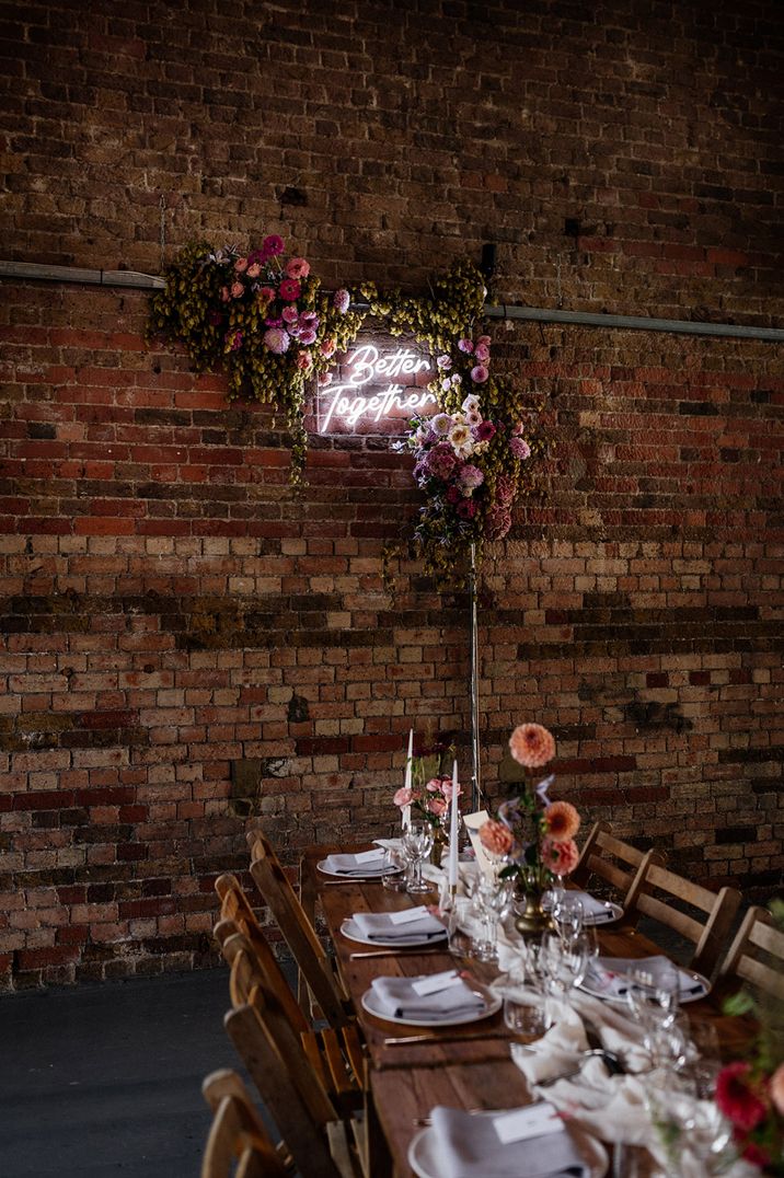 White neon wedding sign reading 'Better Together' decorated with flowers