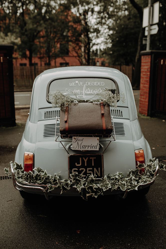 Baby blue vintage wedding car with "we've decided on forever" sign and suitcase decorations