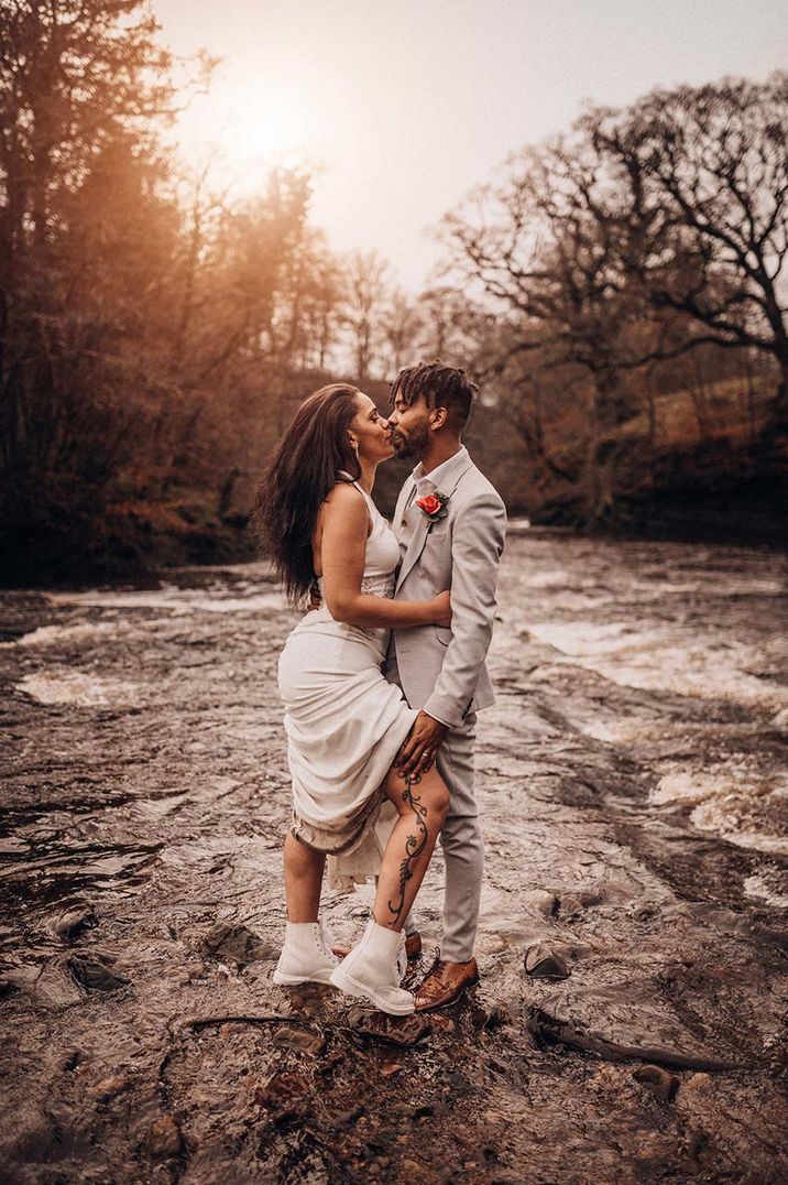 Bride in halter neck wedding dress and wedding Dr Martens and groom in grey suit at Hidden River Cabins