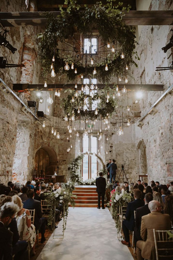 Lulworth Castle wedding with stunning hanging festoon lighting with pampas grass moon gate decorating the altar 