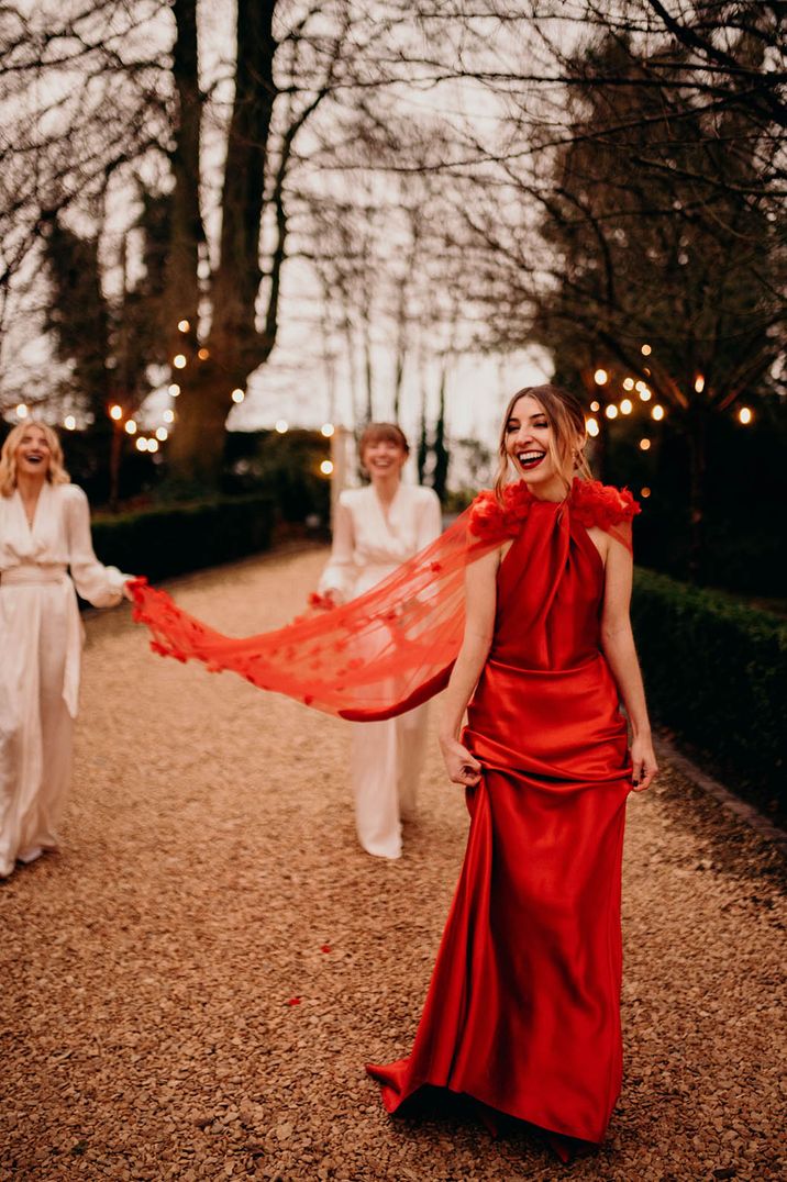 Bride wearing red satin wedding dress with cape at Christmas wedding 