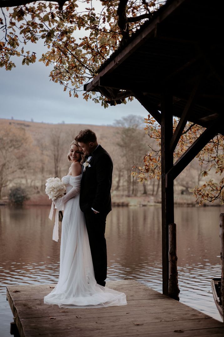 The bride and groom stand by the river at Wyresdale Park in Lancashire 