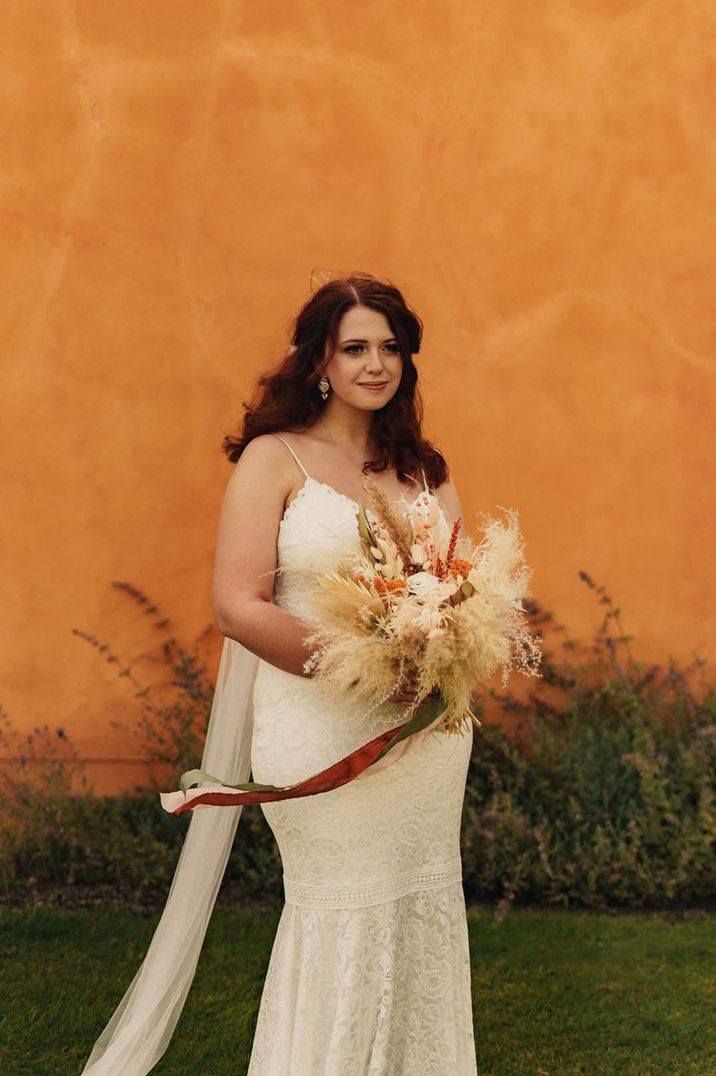 Bride in Grace Loves Lace dropped waist wedding dress holding wedding bouquet with dried wedding flowers 