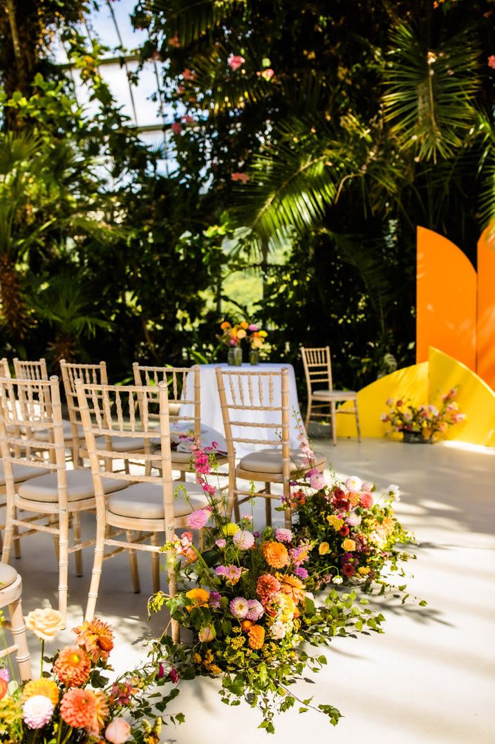 Pink, orange and yellow meadow wedding aisle flowers for summer wedding at a glasshouse wedding venue 