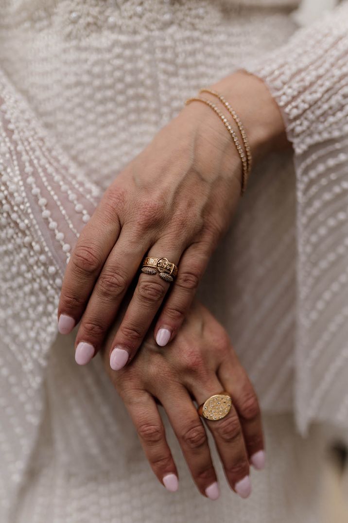 Bride with rounded pale pink nails with gold rings for wedding day 