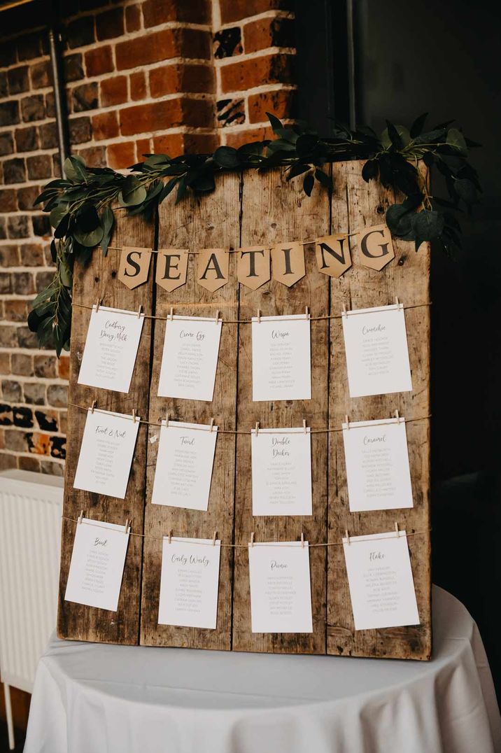 Wooden board DIY seating plan with bunting and foliage decorations on top 