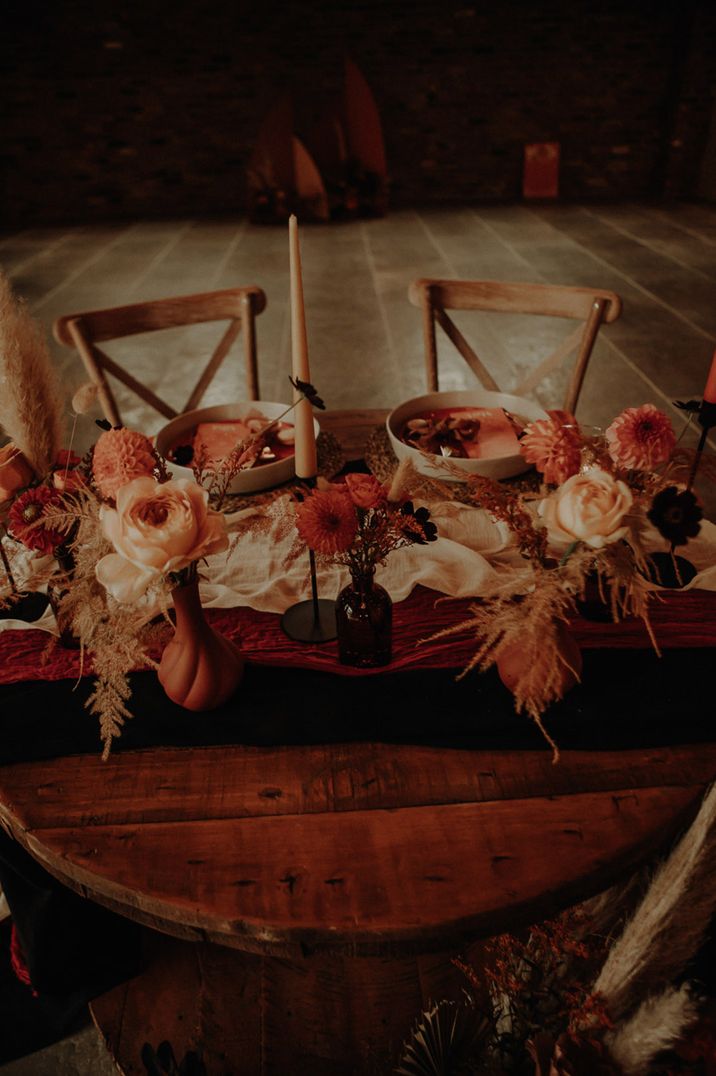 A sweetheart table with soft pink decor and flower arrangements with dahlias 