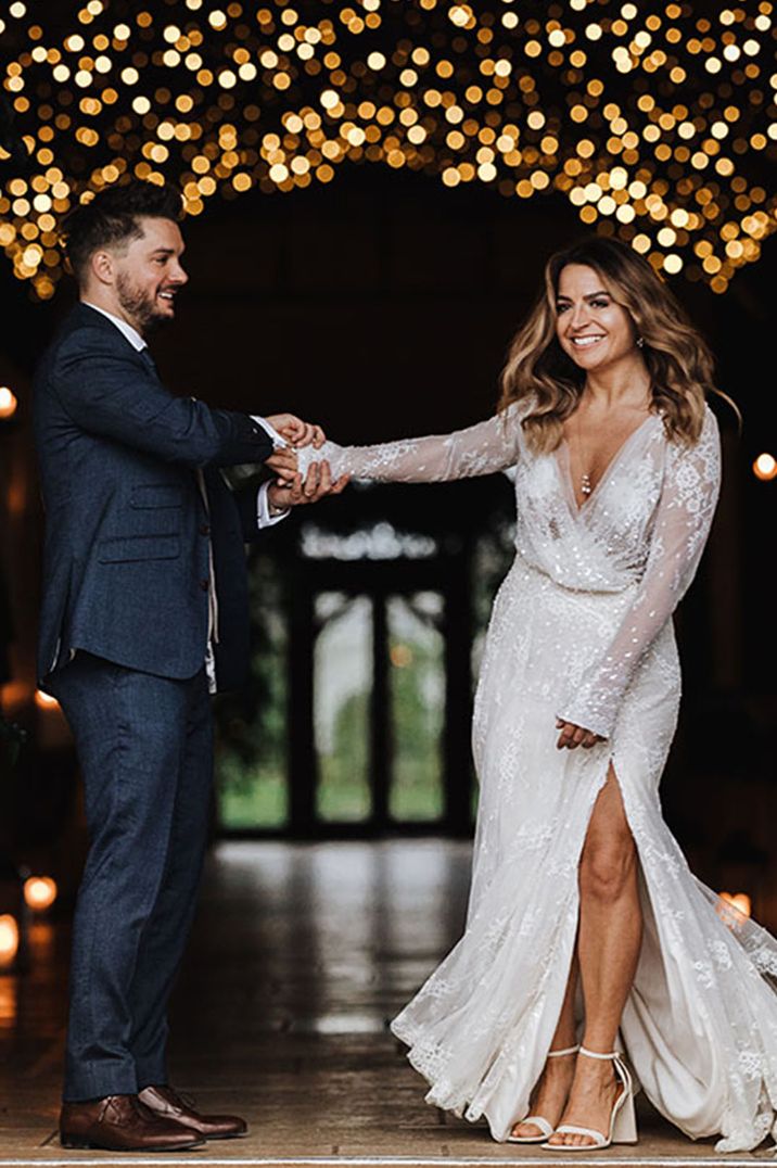 Bride in sparkly wedding dress dancing with groom under magical fairy lights at one of the best winter wedding venues 