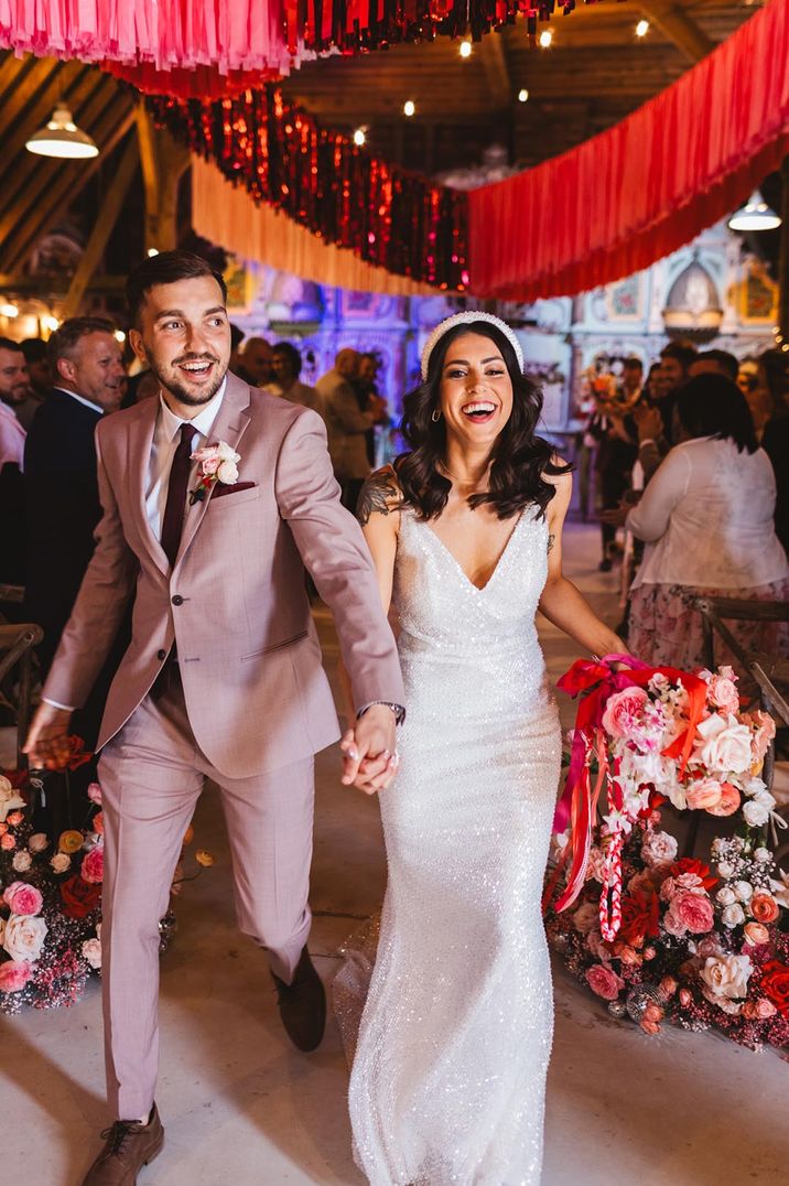 Pink streamers wedding decor at fun fair wedding with bride in sparkly wedding dress and groom in light pink suit 