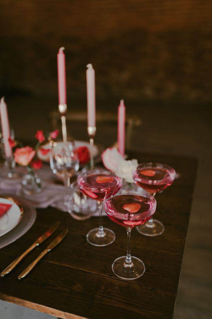 Coupe glasses full of pink cocktails with strawberry slices for Galentine's theme 