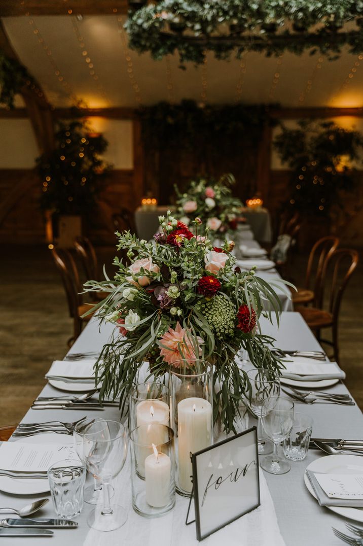 Centrepiece flowers for rustic wedding with green foliage and red and pink roses and dahlias 