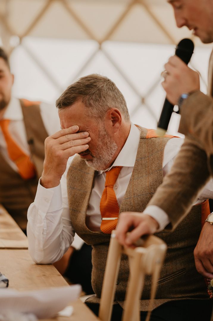 Wedding guest in grey waistcoat and orange tie getting emotional during wedding speech