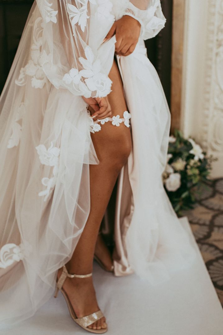 Bride wears appliqué styled white garter with flowers 