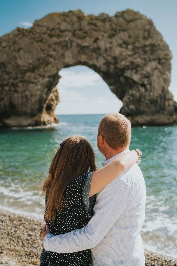 Couple embrace as they look out at the view at Durdle Door Bay