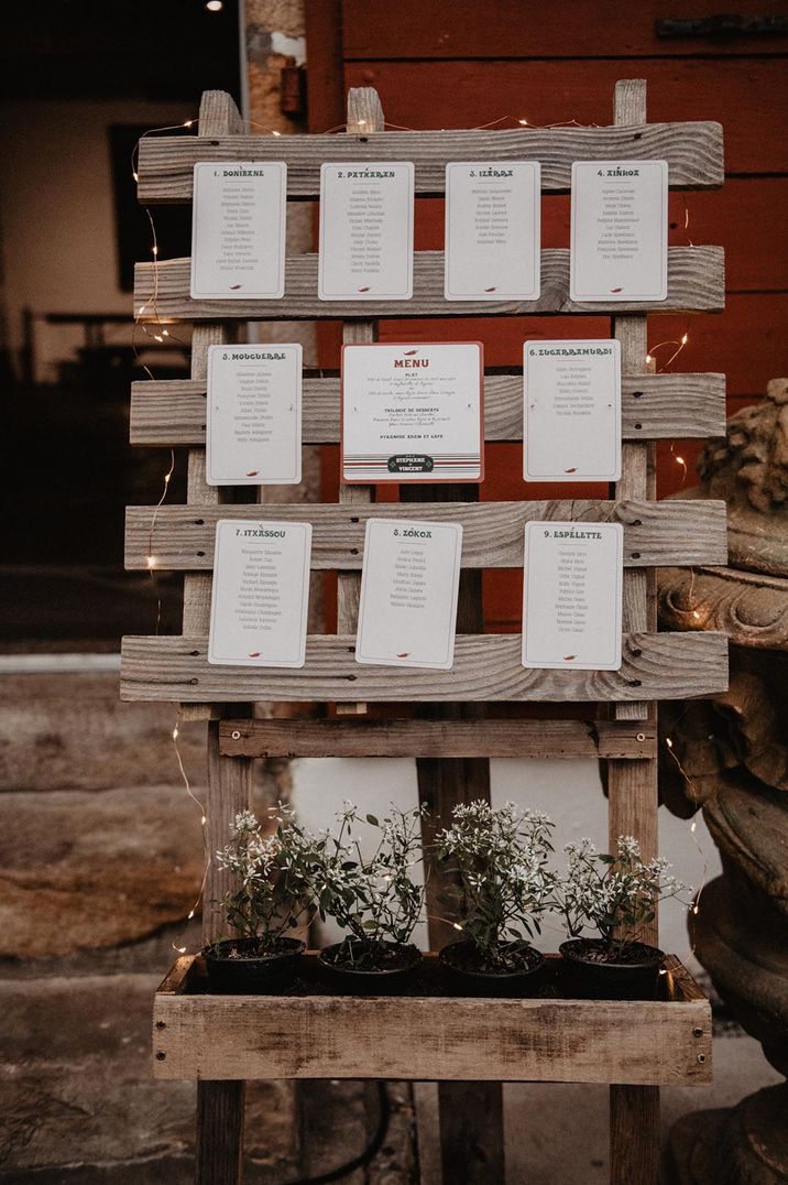 Grey wooden pallet table plan with small string fairy lights and small potted plants