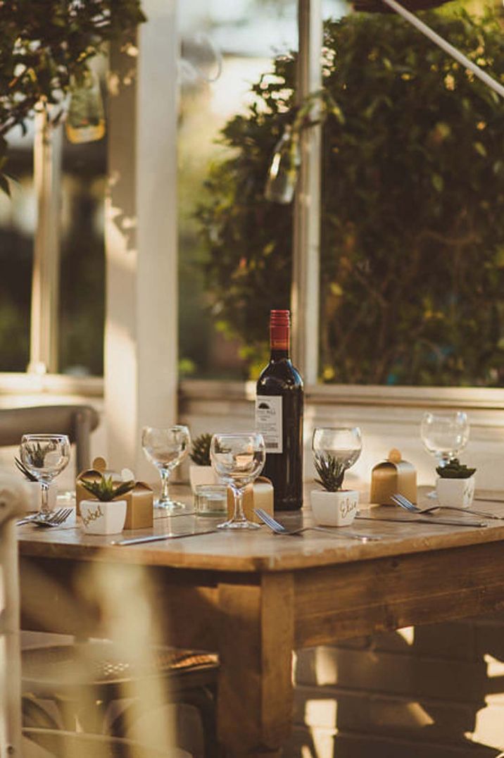 Red wine and wine glasses on wooden table at Clifton Nurseries London glasshouse wedding venue 