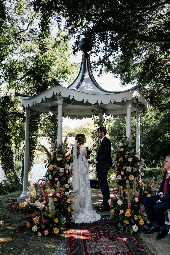 Outdoor gazebo wedding ceremony with colourful wedding flower column arrangements with pampas grass 