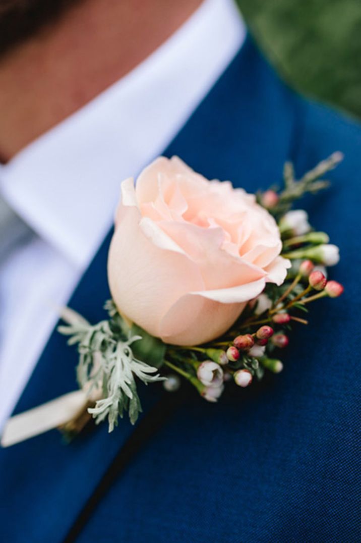 Peach rose buttonhole groom's accessory to complement navy blue suit 