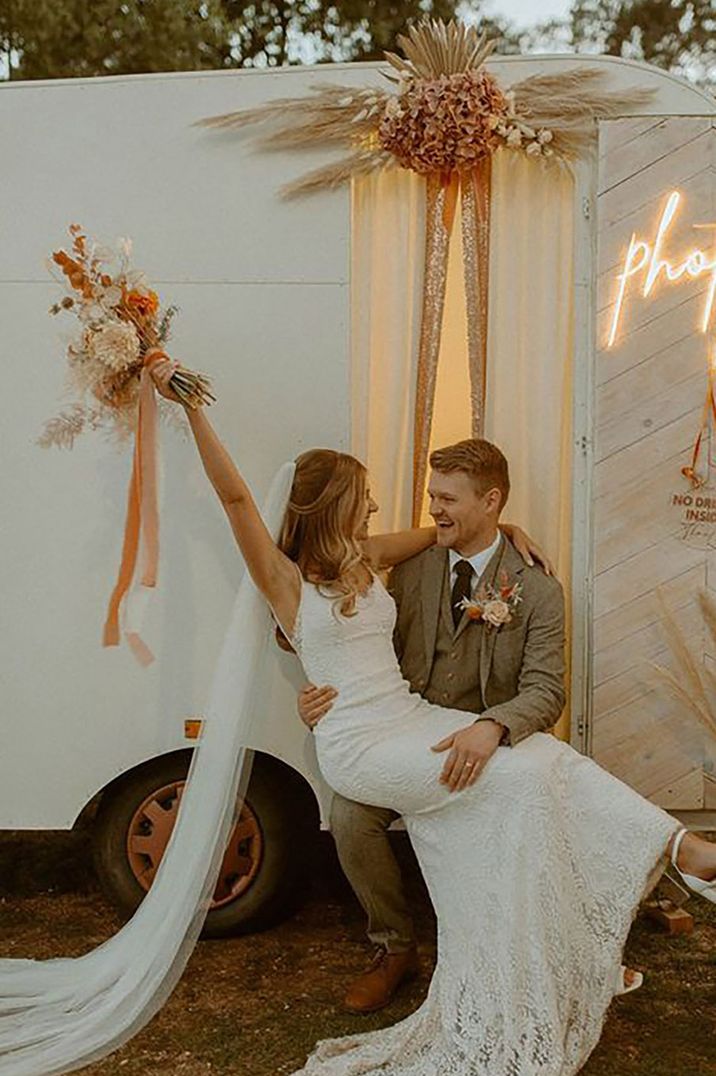 Bride and groom posing outside photo booth at their wedding reception by Paige Grace Photography