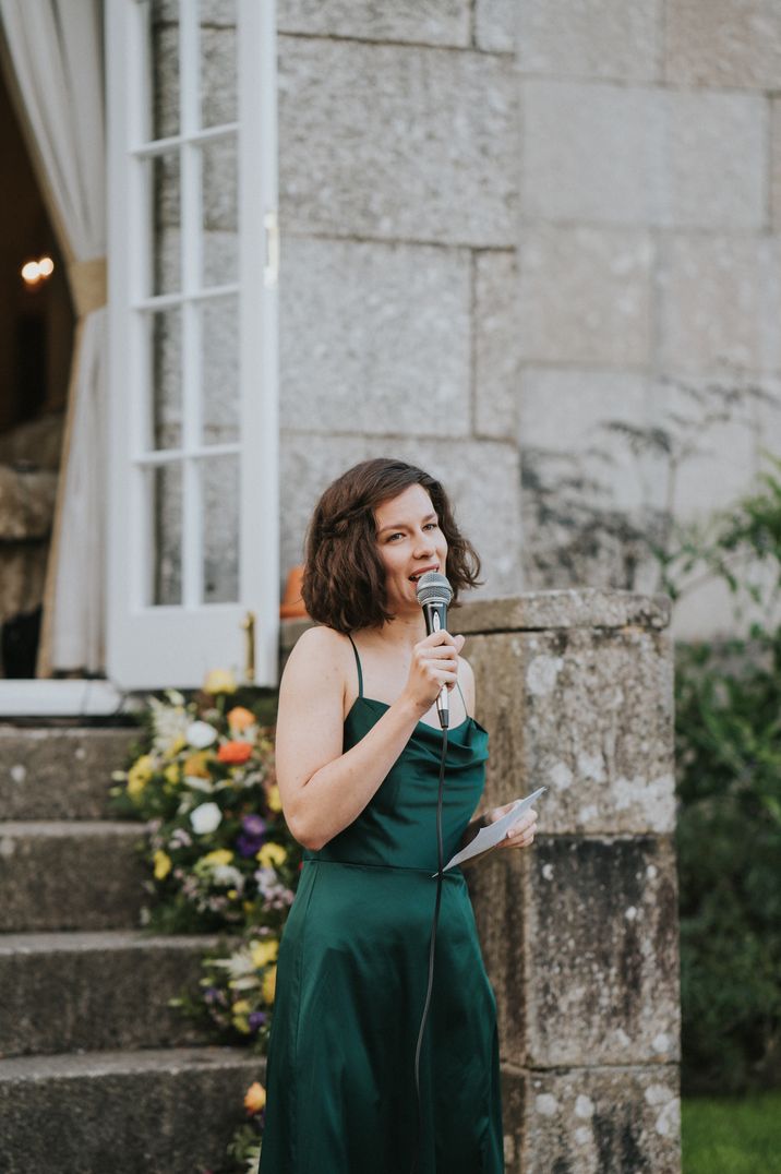 Person making wedding speech in dark green velvet slip dress 