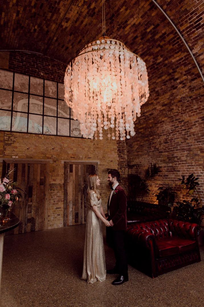 Bride and groom standing under large paper chandelier at 100 Barrington